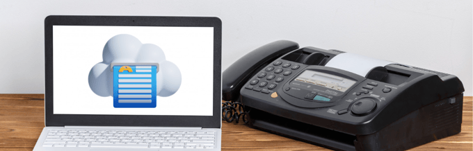 Un portátil con un servicio de fax en línea junto a una mesa de madera.