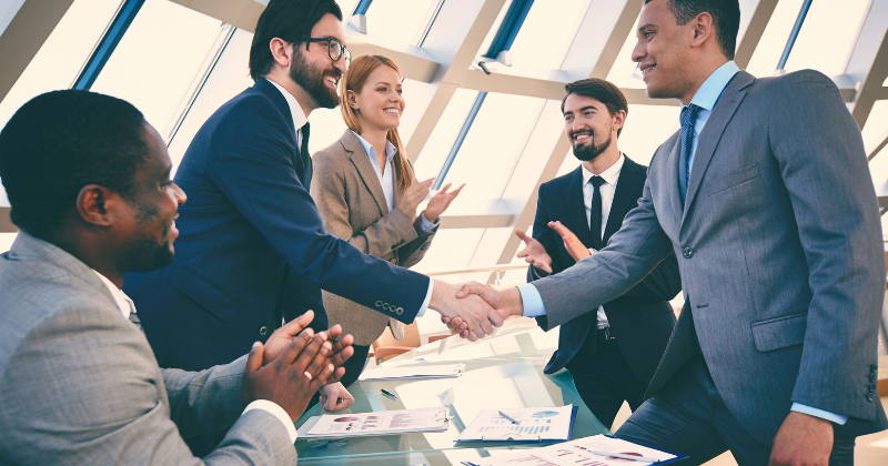 Gente de negocios dándose la mano en una oficina, finalizando un contrato utilizando plantillas de contratos de negocios.