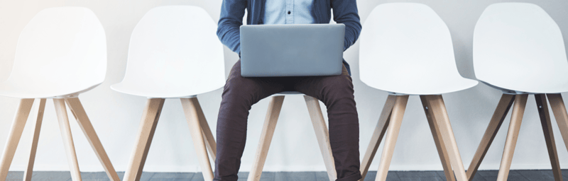 A woman sitting on a chair with a laptop on her lap.