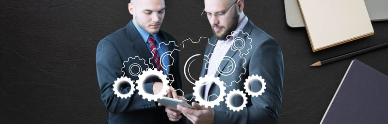 Two businessmen are looking at a tablet with gears on it.