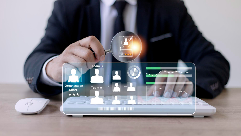 A man in a suit is looking at a computer screen with people on it.